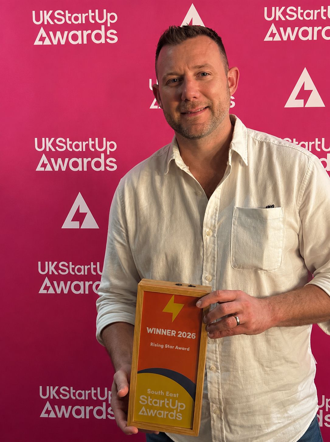 Founder Dennis McCarthy holding the UK Startup Awards 2026 Rising Star trophy at the South East regional final
